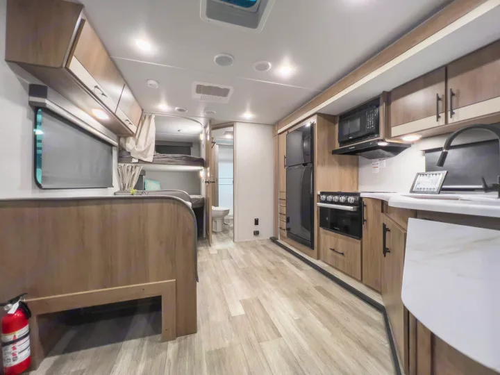 Spacious RV rental interior featuring a modern kitchen, living area, and bunk beds for comfortable travel.. Grand Design Imagine XLS 2023