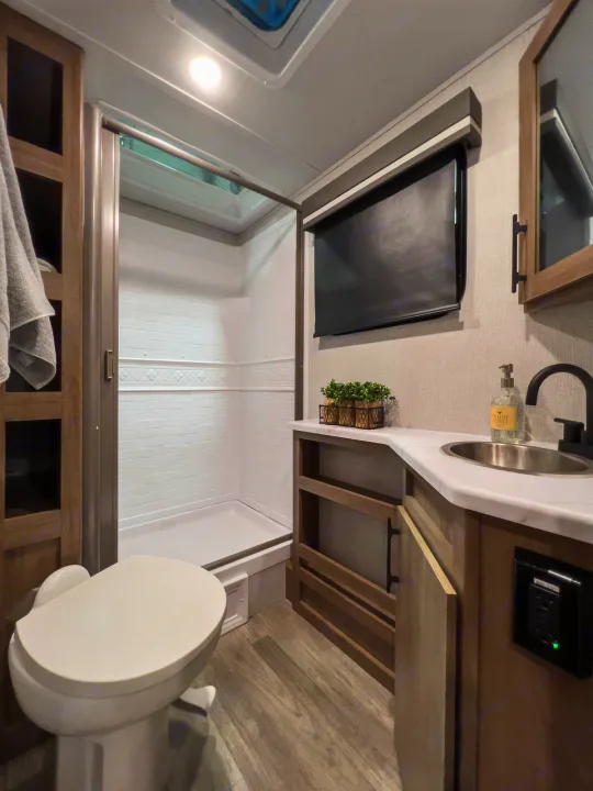 Modern RV rental bathroom with shower, toilet, and vanity. Compact yet complete amenities for travel comfort.. Grand Design Imagine XLS 2023