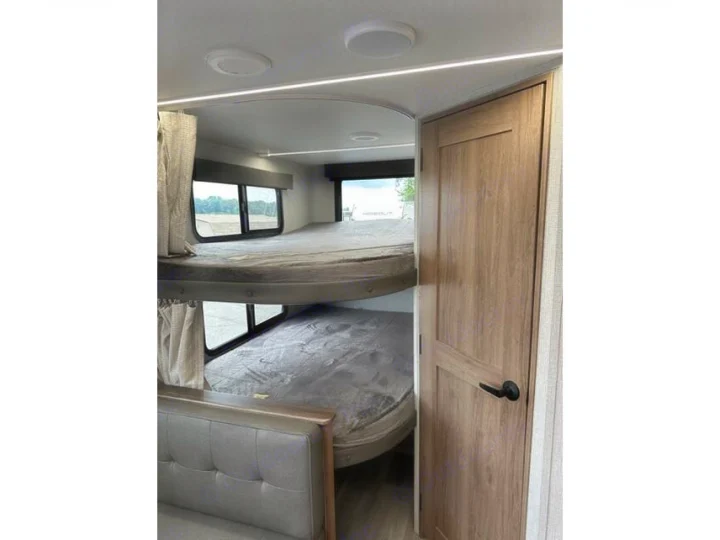 RV rental interior features bunk beds with windows, providing comfortable sleeping space.. Grand Design Imagine XLS 2023