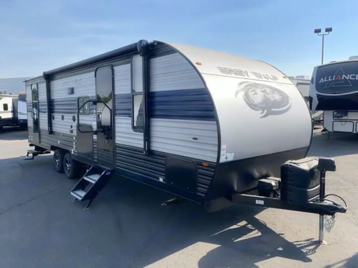 This spacious Grey Wolf travel trailer, perfect for an RV rental, features multiple entry doors and an awning, parked on a sunny lot.. Forest River Cherokee Grey Wolf 2021