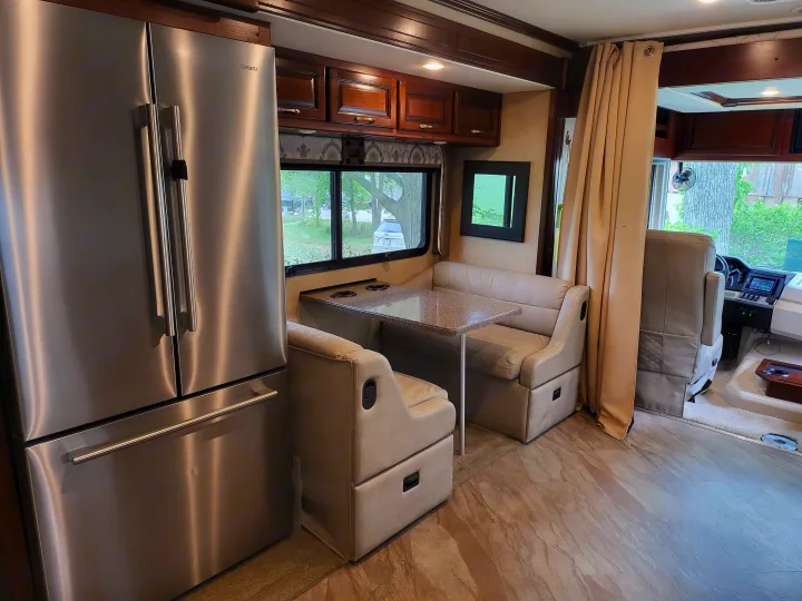 Modern rv rental interior: stainless fridge, dinette, and cockpit. Ready for adventure, comfort, and scenic travel.. Fleetwood Bounder 2017