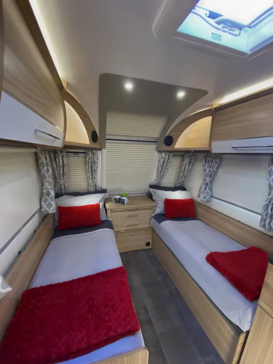 Interior of an RV rental showing a twin bedroom setup with cozy bedding, practical storage, and skylight.. Bailey Pheonix 640 2022