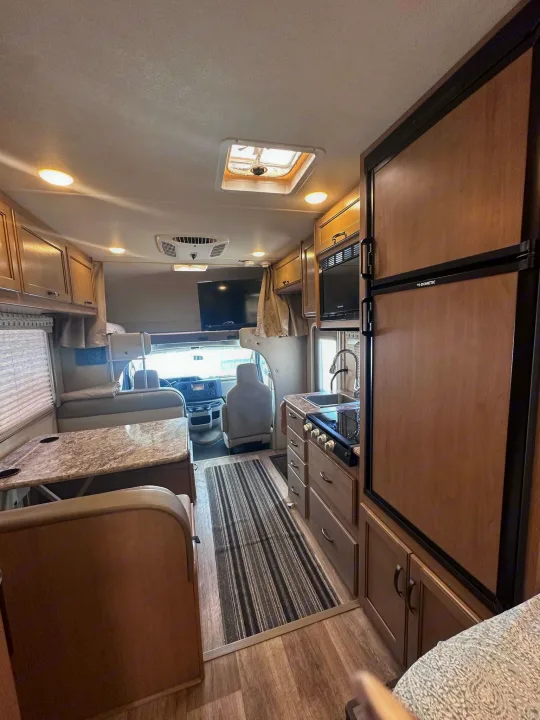 Explore this RV rental's cozy interior, featuring a full kitchen, dining area, and front cab-over bunk for comfortable road trips.. Thor Motor Coach Four Winds 2019