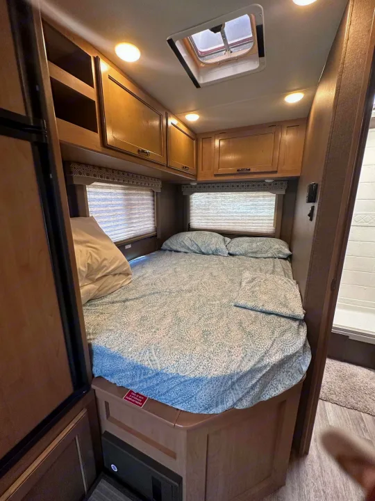 Explore this cozy RV rental bedroom. It features a comfortable bed, storage cabinets, and a skylight for natural light.. Thor Motor Coach Four Winds 2019