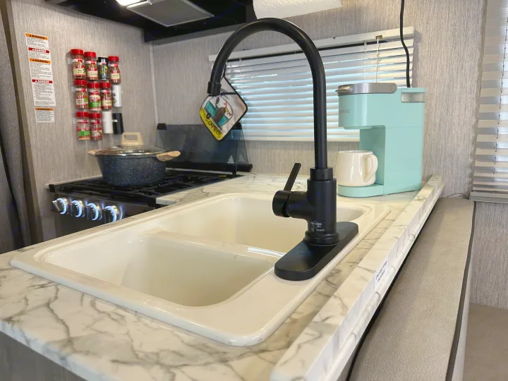 RV rental kitchen with sink, stove, and Keurig coffee maker. Fully equipped for meals on your road trip.. Forest River Coachmen Freelander 2022