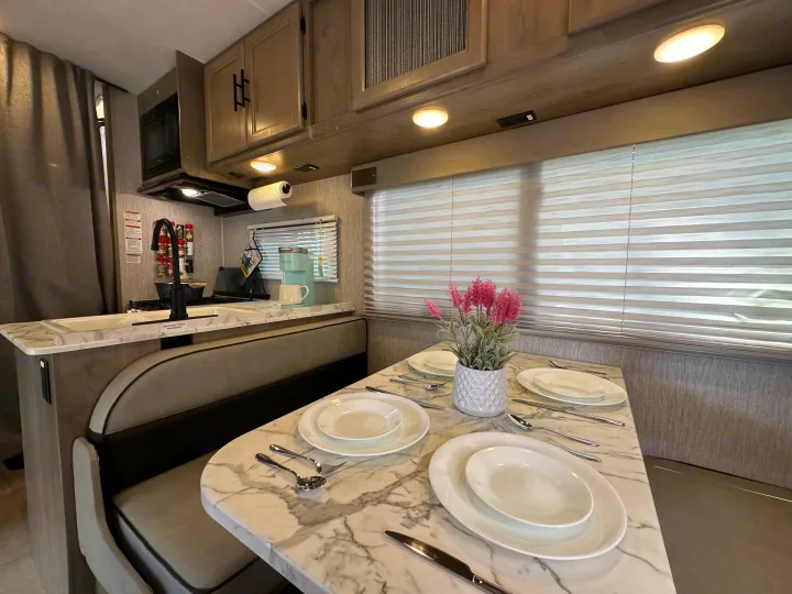 RV rental: Compact kitchen with microwave, sink, and an inviting dinette with a marble-look table set for meals.. Forest River Coachmen Freelander 2022