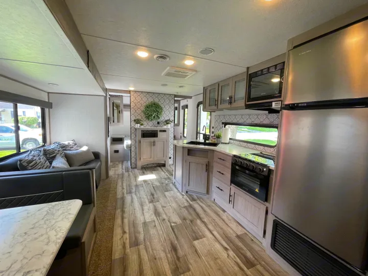 Modern RV rental interior with a spacious kitchen, dining area, and comfy living space. Perfect for travel!. Coleman 263BH 2022