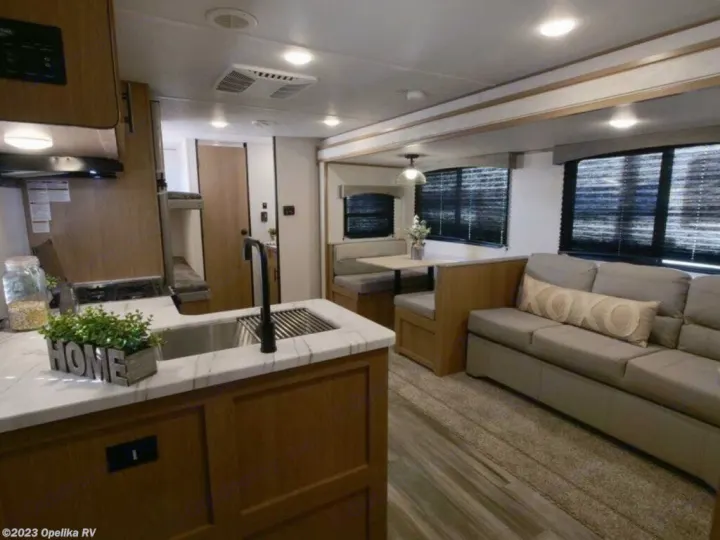 Spacious RV rental interior with a functional kitchen, cozy dining area, living room sofa, and bunks. Ready for travel!. Forest River Avenger LE 2022