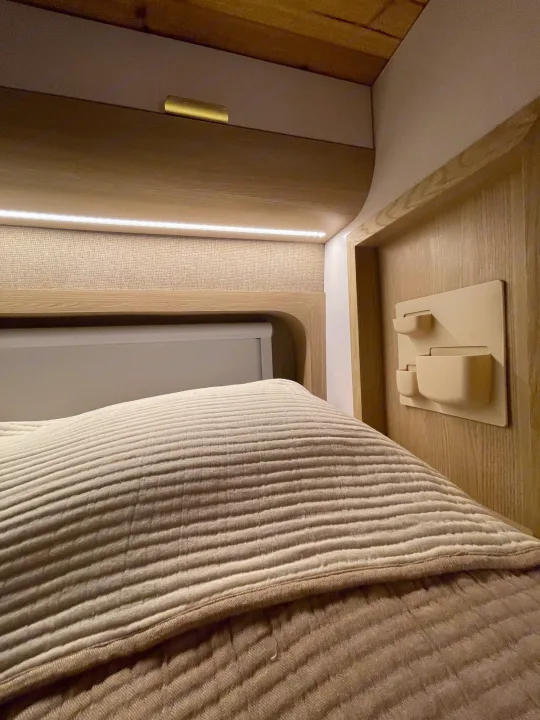 Experience comfort in this modern **rv rental** bedroom featuring a plush bed, ambient lighting, and clever wall storage.. Dodge Ram Promaster 3500 C/V HR 159 EXT 2023