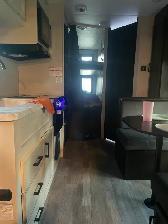 Inside an RV rental: a compact kitchen, bunk beds, and a dining nook, all in a modern camper interior.. Jayco Jay Flight 2023