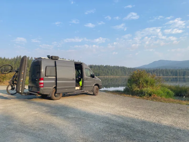 Grey camper van by a tranquil lake with bike, ideal for an RV rental adventure.. Mercedes Sprinter 2016