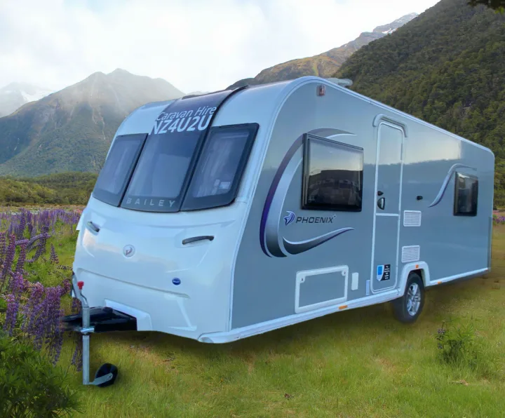 Modern grey and white caravan RV rental in a scenic mountain setting with purple flowers. Ideal for your next nature adventure.. Bailey x 2022