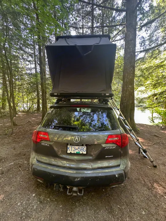 This Acura MDX SUV with an open rooftop tent offers a great RV rental option for camping by a lake in the woods.. Other Other 2007