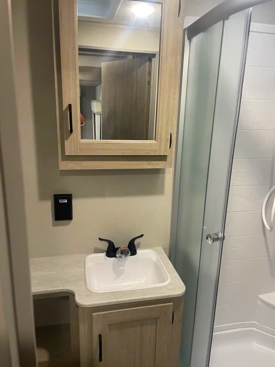 RV rental's compact bathroom: features a vanity, sink, medicine cabinet, and shower with frosted glass door.. Coachman Catalina, Legacy edition 343BHTS 2024