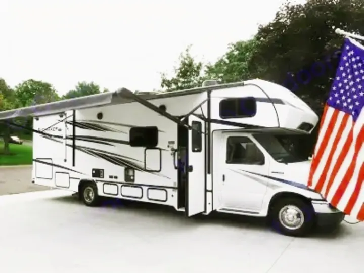 White RV rental with awning extended, American flag, parked on pavement. Ideal for travel, vacations & road trips.. Forest River Sunseeker Classic 2023