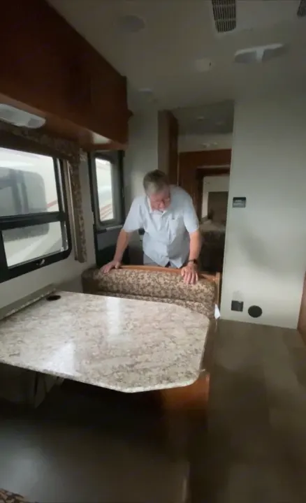 Inside RV rental: Older man inspects dinette table.. Jayco Redhawk 2017