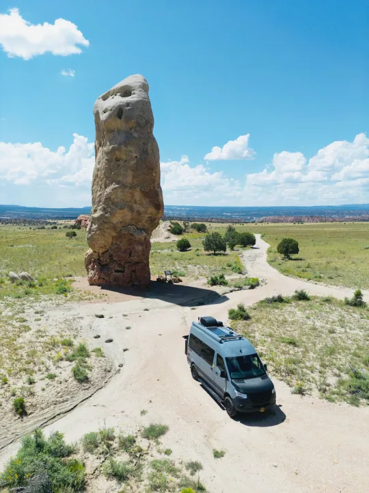 Explore stunning landscapes with an rv rental! Grey camper van near a towering desert rock formation under a bright blue sky.. Synergy Mercedes-Benz Sprinter 2022
