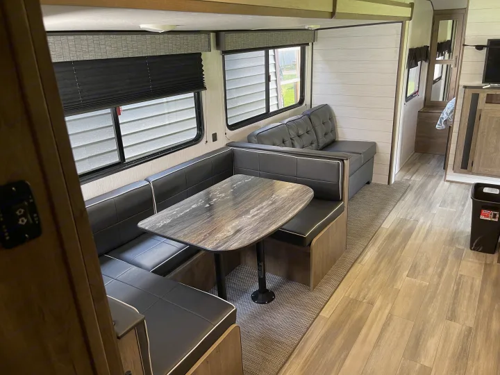 Explore this RV rental's modern interior: a stylish dinette with dark seating, marbled table, and plank flooring.. Heartland RVs Pioneer 2022