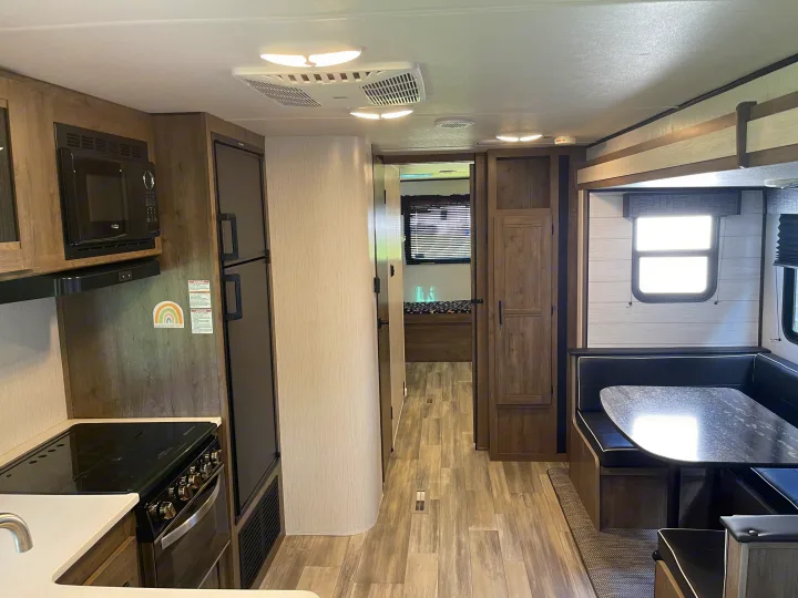 Step inside this modern rv rental, showcasing a full kitchen, comfortable dinette, and private bedroom area.. Heartland RVs Pioneer 2022