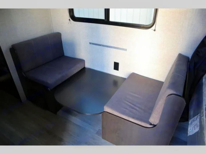 RV rental dinette with grey upholstered benches and dark table, providing seating and dining space inside.. Jayco Jay Flight SLX Baja Edition 2022