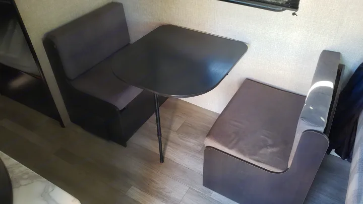 RV rental dinette area: a compact black table centered between two upholstered gray bench seats in a modern interior.. Jayco Jay Flight SLX Baja Edition 2022
