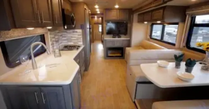 Modern RV rental interior showcasing a full kitchen, dinette, and cozy living space with a TV and fireplace.. Thor Miramar 2022