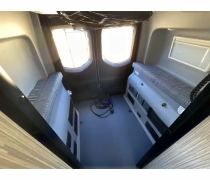 Explore this RV rental's rear interior: two side benches, large windows, providing versatile space for travel.. Winnebago Revel 2023