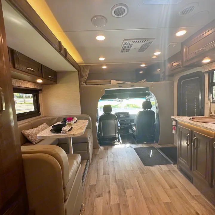 Inside a modern RV rental: a comfortable dinette, functional kitchen, and driver's area visible. Bright and spacious.. Jayco Melbourne 2022
