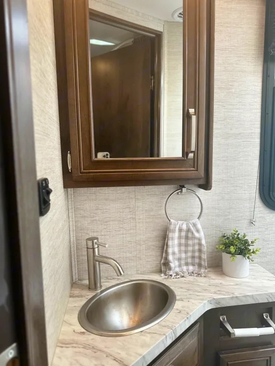 This RV rental features a clean, well-appointed bathroom vanity with a sink, mirror cabinet, and modern fixtures.. Jayco Melbourne 2022