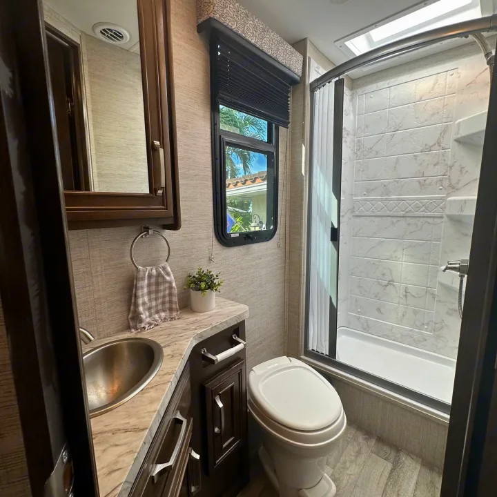 Inside this RV rental bathroom: a modern sink vanity, toilet, and a well-lit shower. Compact yet fully equipped for comfortable travel.. Jayco Melbourne 2022
