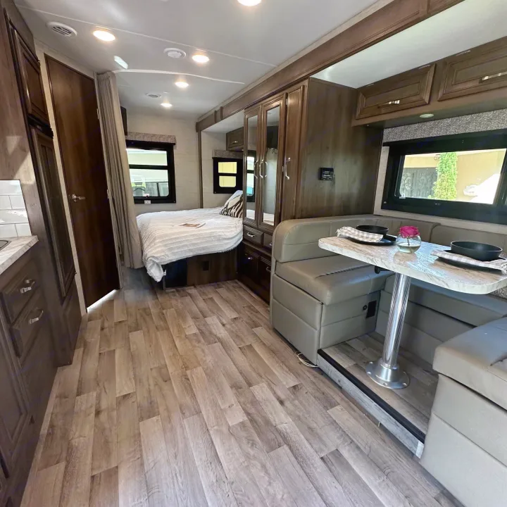 Step inside this cozy RV rental, featuring a comfortable dinette, a compact kitchen, and a sleeping area with a bed.. Jayco Melbourne 2022