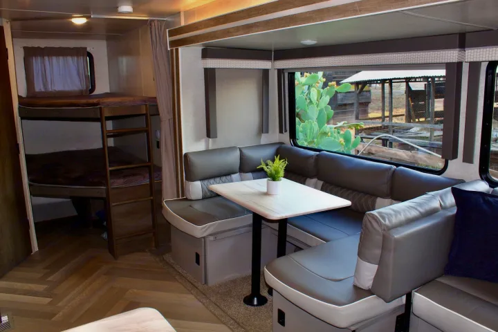 Spacious RV rental interior featuring a modern dining booth, bunk beds, and large windows.. Forest River Wildwood 2021