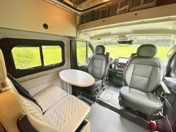 Spacious RV rental interior: swiveled front seats, adjustable table, and cozy rear bench seating with storage.. Winnebago Solis 2023