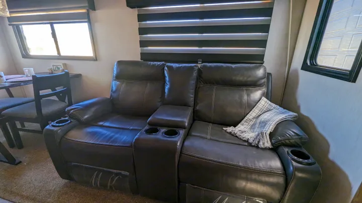 Cozy RV rental living area featuring a reclining loveseat with cup holders and nearby dining space.. Forest River Cherokee Alpha Wolf 2021