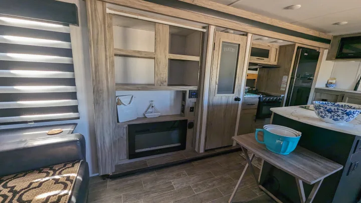 RV rental interior showing modern living area with fireplace, shelving, pantry, and kitchen amenities.. Forest River Cherokee Alpha Wolf 2021