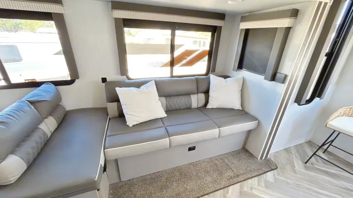 Spacious RV rental interior featuring modern gray bench seating, bright windows, and stylish flooring.. Forest River Wildwood 2022
