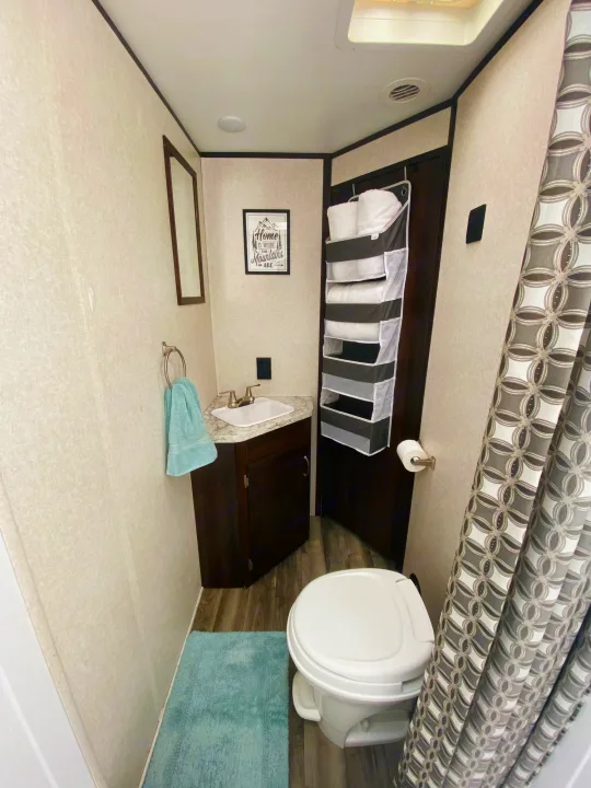 Compact RV rental bathroom with sink, toilet, shower, and clever hanging storage for essentials.. Jayco Jay Flight SLX 2018