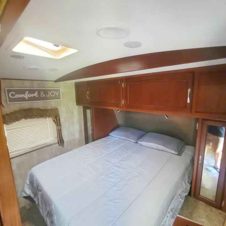 Comfortable RV rental bedroom featuring a full bed, overhead cabinetry, and a skylight for a bright, relaxing stay.. Winnebago Ultralite 2014