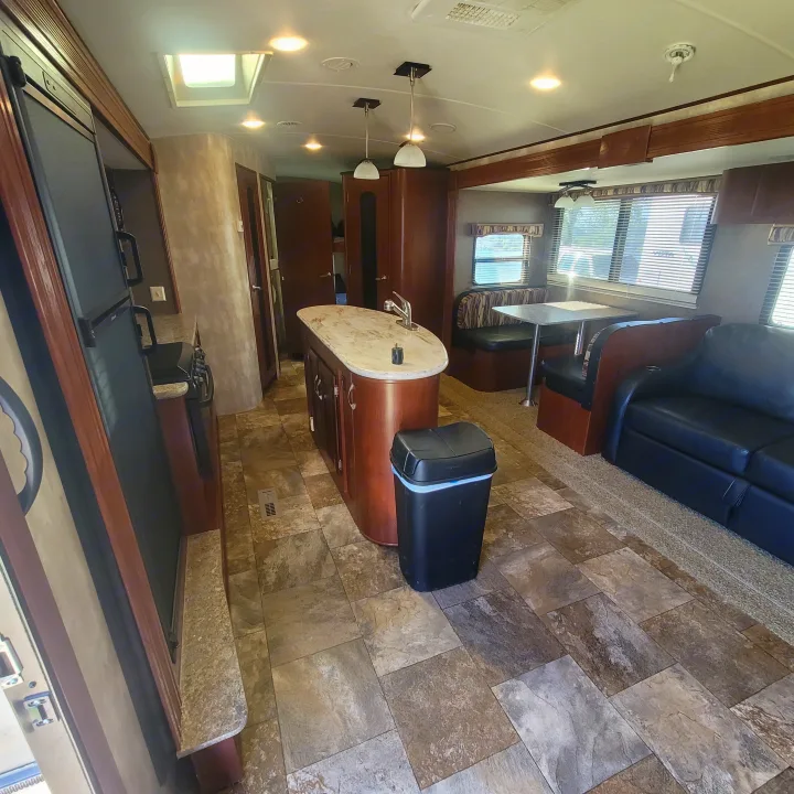 Explore this RV rental's inviting interior featuring a central kitchen island, dining booth, and spacious living area.. Winnebago Ultralite 2014
