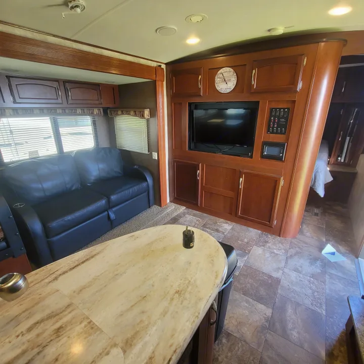 Interior of a comfortable RV rental: living area with black sofa, wood entertainment center, and large counter.. Winnebago Ultralite 2014