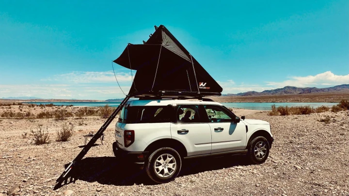 White Bronco Sport RV rental with open rooftop tent by a desert lake. Ideal for overland camping adventures.. Ford Bronco Sport 2022