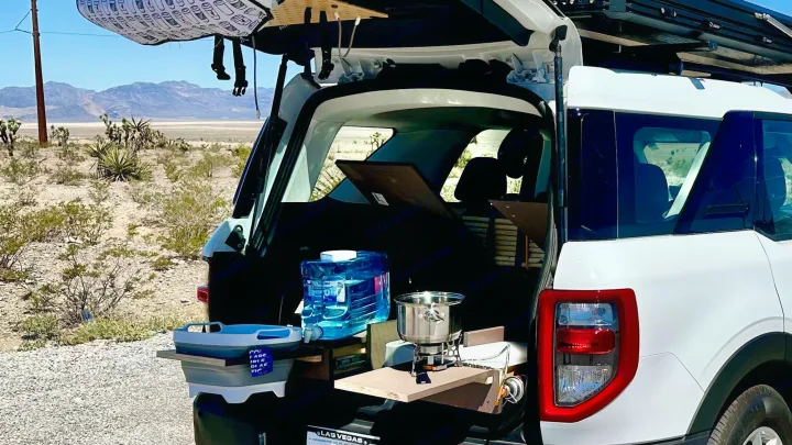 RV rental ready for adventure: Tailgate kitchen setup with stove, water, and collapsible sink in a desert landscape.. Ford Bronco Sport 2022