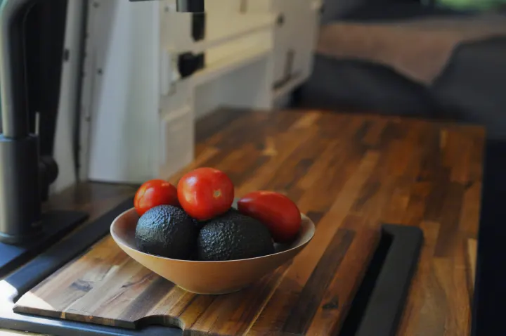 Bowl of fresh avocados and tomatoes on a wooden counter in an RV rental. Ideal for healthy travel meals.. Freightliner Sprinter 2020