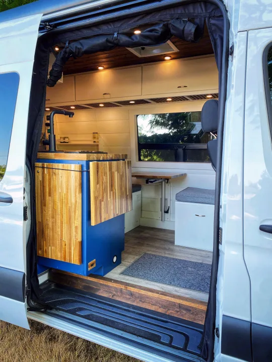 Custom camper van interior, perfect for rv rental. Features kitchen, dining table, and cozy seating.. Freightliner Sprinter 2020