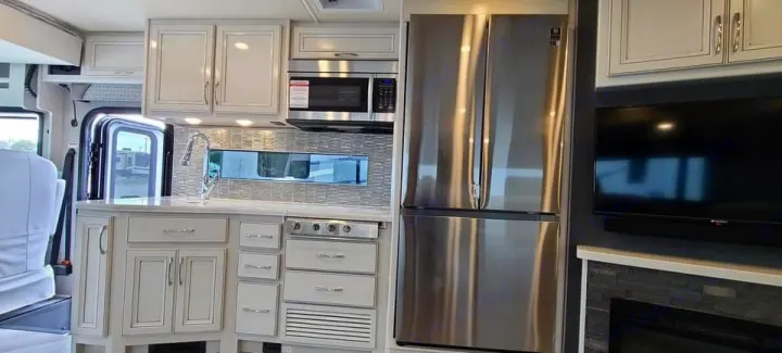 Explore this spacious RV rental interior: a modern kitchen with stainless steel appliances, sink, and a cozy living area with TV & fireplace.. Fleetwood Other 2022