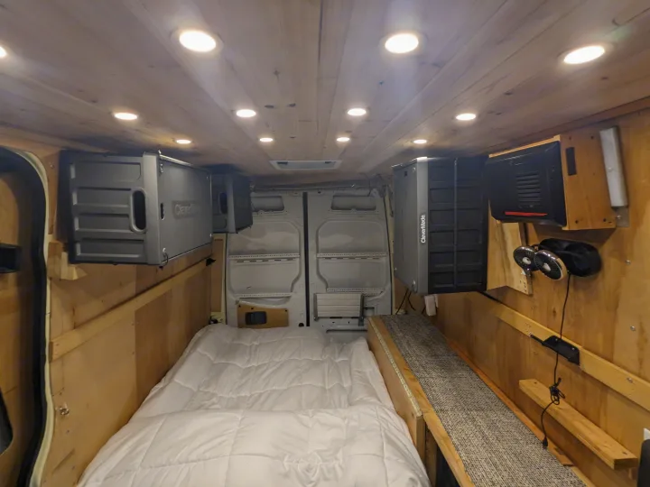 Inside a custom RV rental camper van: wood ceiling with lights, comfy bed, wall-mounted storage, and fans. Ready for adventure!. Mercedes Benz Sprinter 2500 2014