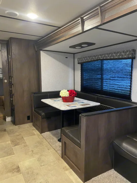 RV rental: U-shaped dinette with black booth seating, marble table, flowers, and large window.. Dutchmen Coleman Lantern 2019