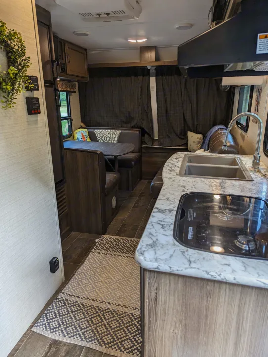 Discover this well-equipped RV rental's interior, featuring a bright kitchen with sink/stove and a cozy dinette.. Keystone RV Bullet Crossfire 2018