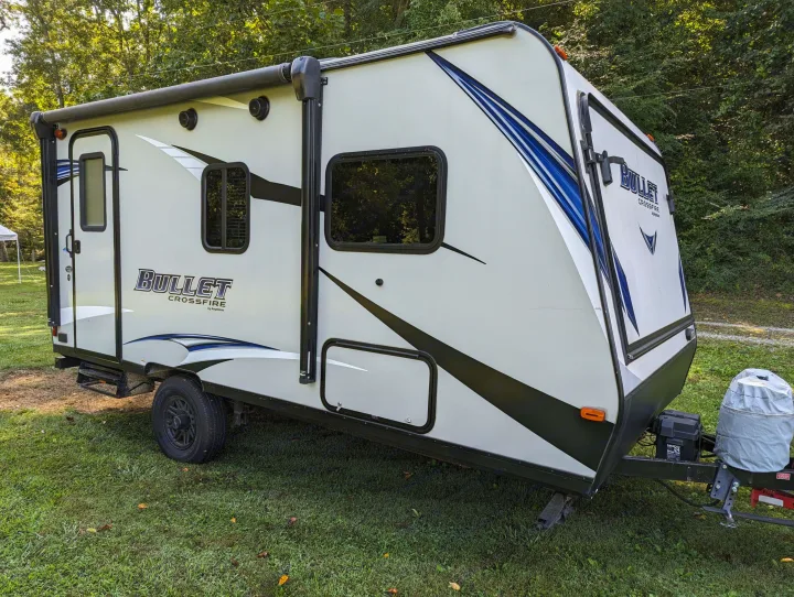 A light-colored Bullet Crossfire rv rental travel trailer parked on grass, ideal for your next camping adventure.. Keystone RV Bullet Crossfire 2018