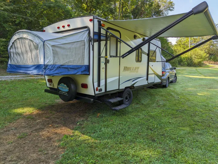 An RV rental: Bullet Crossfire travel trailer with pop-out bed and awning, parked on grass for camping.. Keystone RV Bullet Crossfire 2018